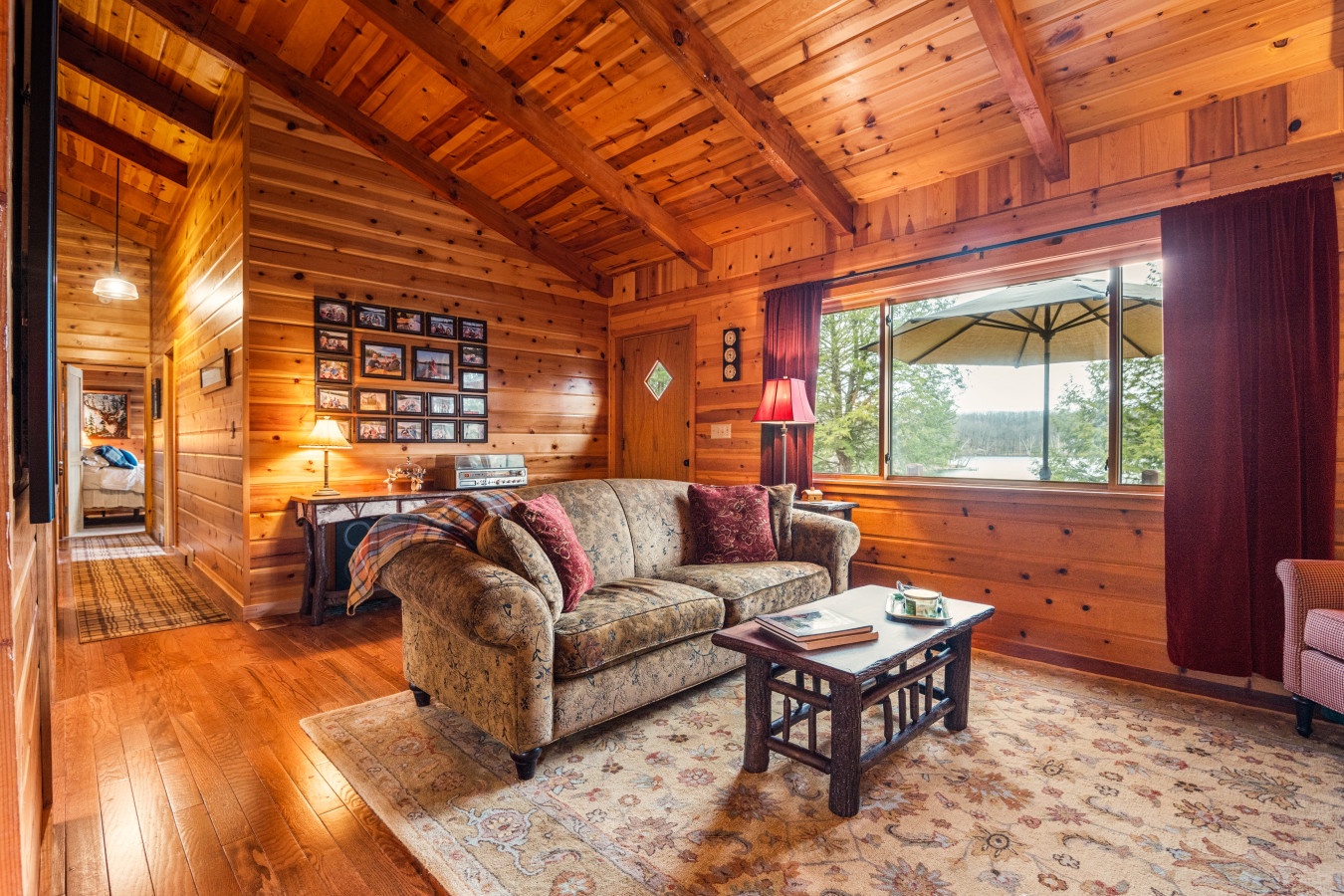 Sink into the plush sofa beneath soaring wood beams, where warm lamplight and nature views create your perfect retreat.