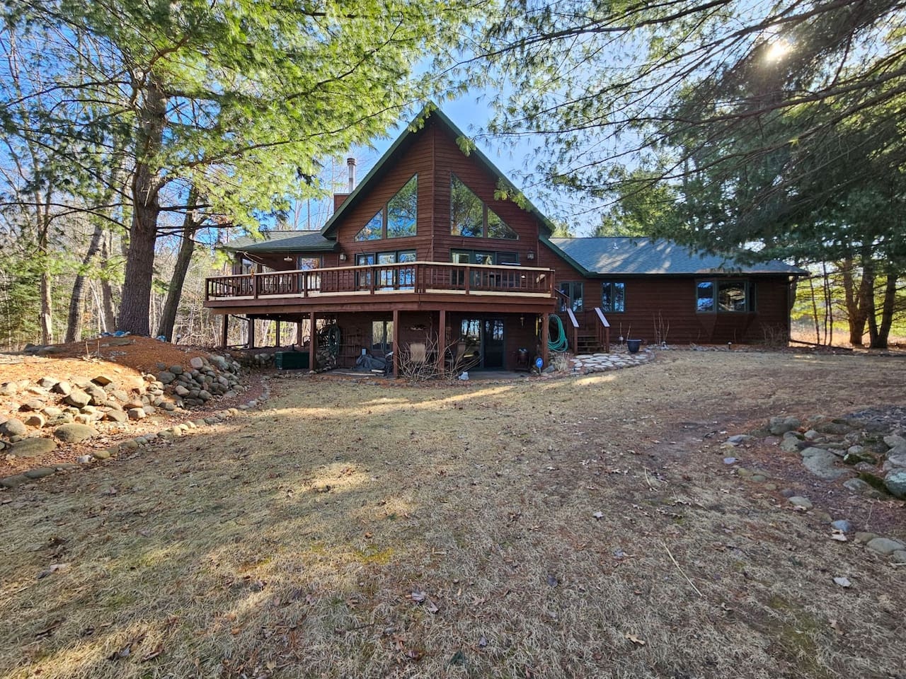 Rustic log cabin nestled among towering trees, offering a peaceful woodland retreat with spacious deck and natural surroundings.