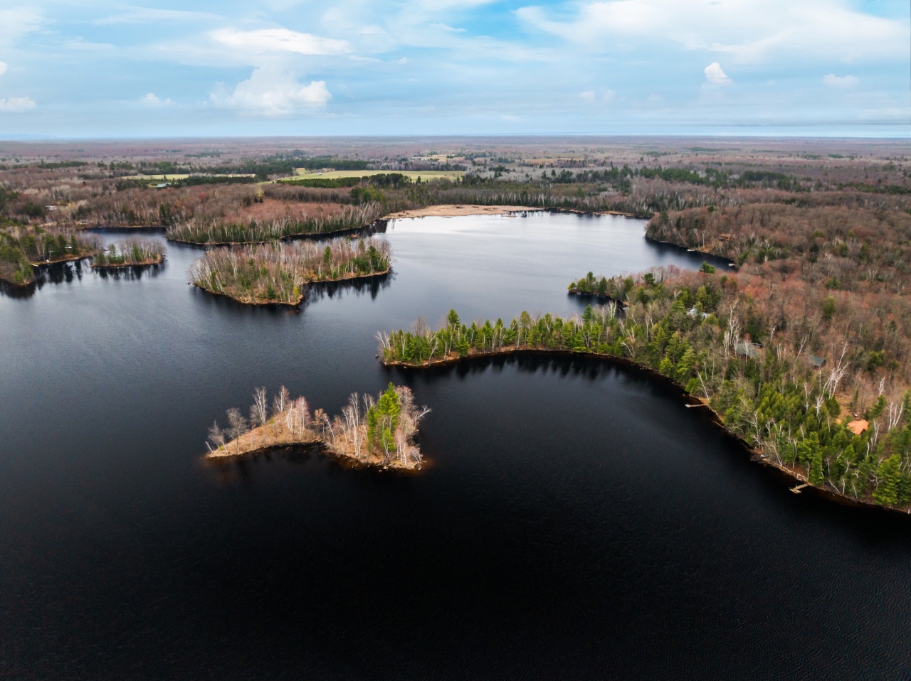 Stunning aerial view showcasing pristine lakes dotted with forested islands and surrounded by vast wilderness stretching to the horizon.
