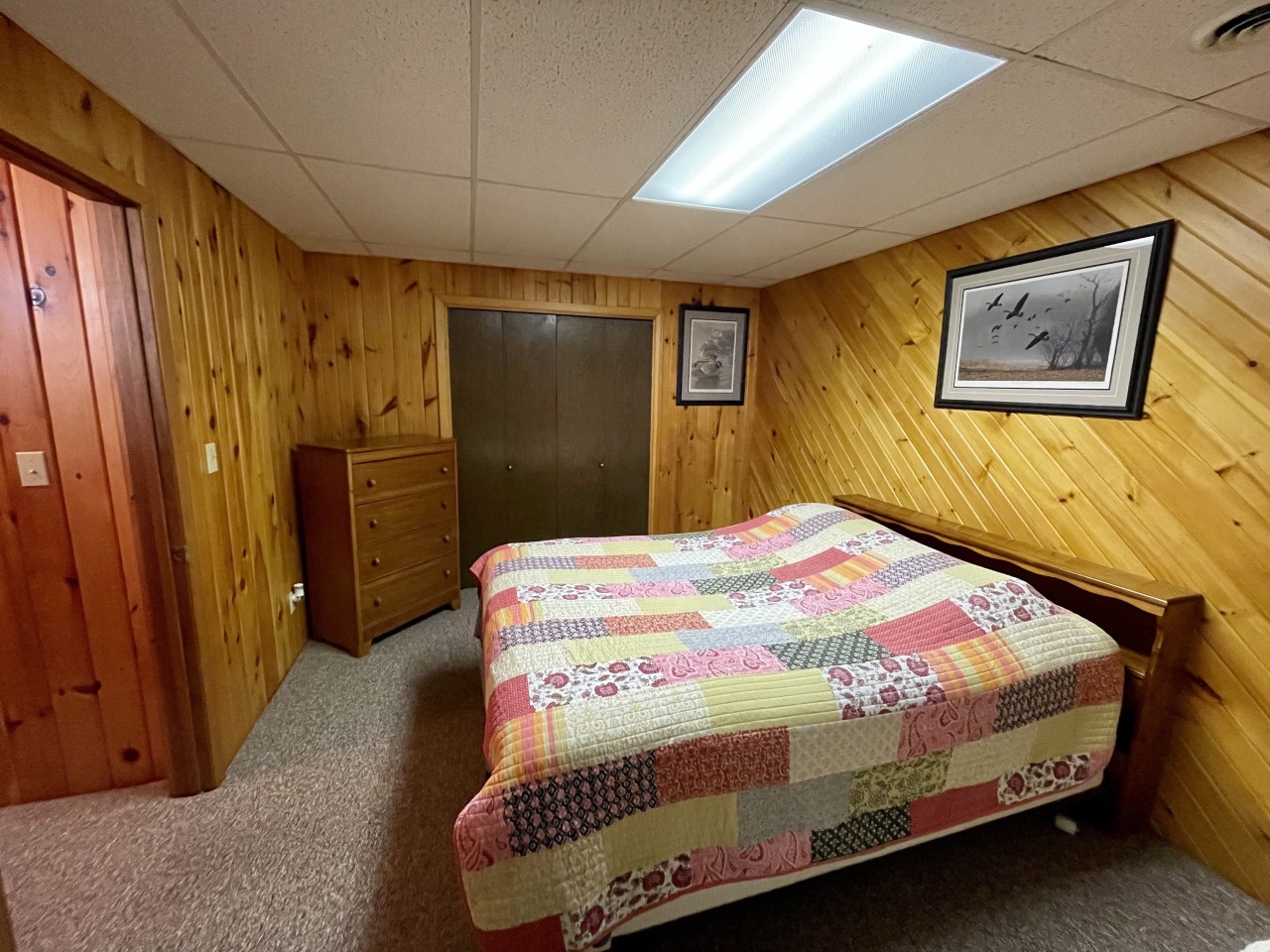 Relax in your cozy wood-paneled bedroom with charming quilt bedding and rustic cabin charm.