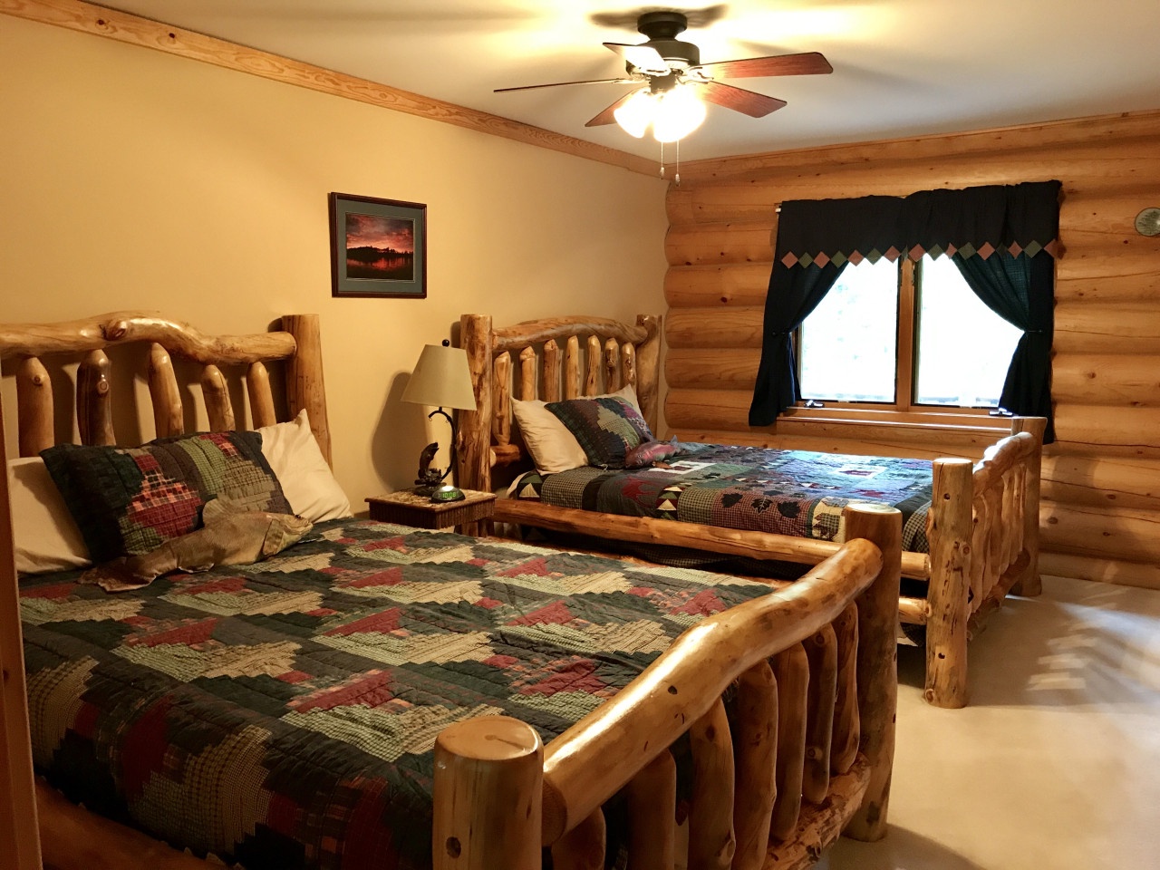 Cozy up in your rustic twin bedroom featuring handcrafted log beds with colorful quilts and authentic cabin charm.