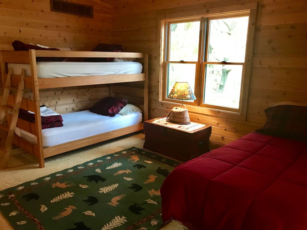 Cozy cabin bedroom with rustic bunk beds and cheerful forest-themed bedding creates perfect sleeping space for your group retreat.