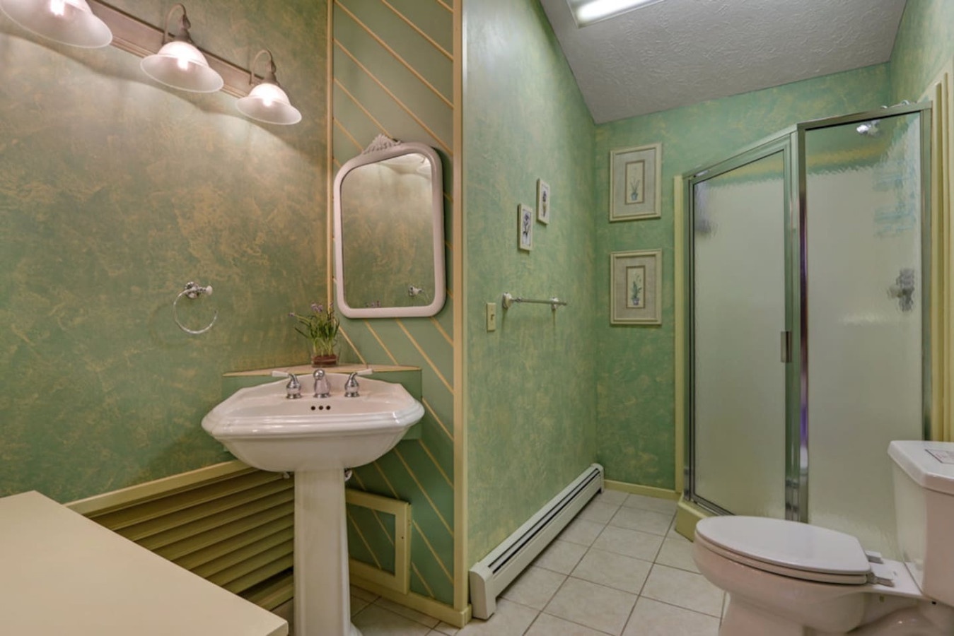 Refresh in your private bathroom featuring a walk-in shower, classic pedestal sink, and charming green décor that creates a spa-like retreat.