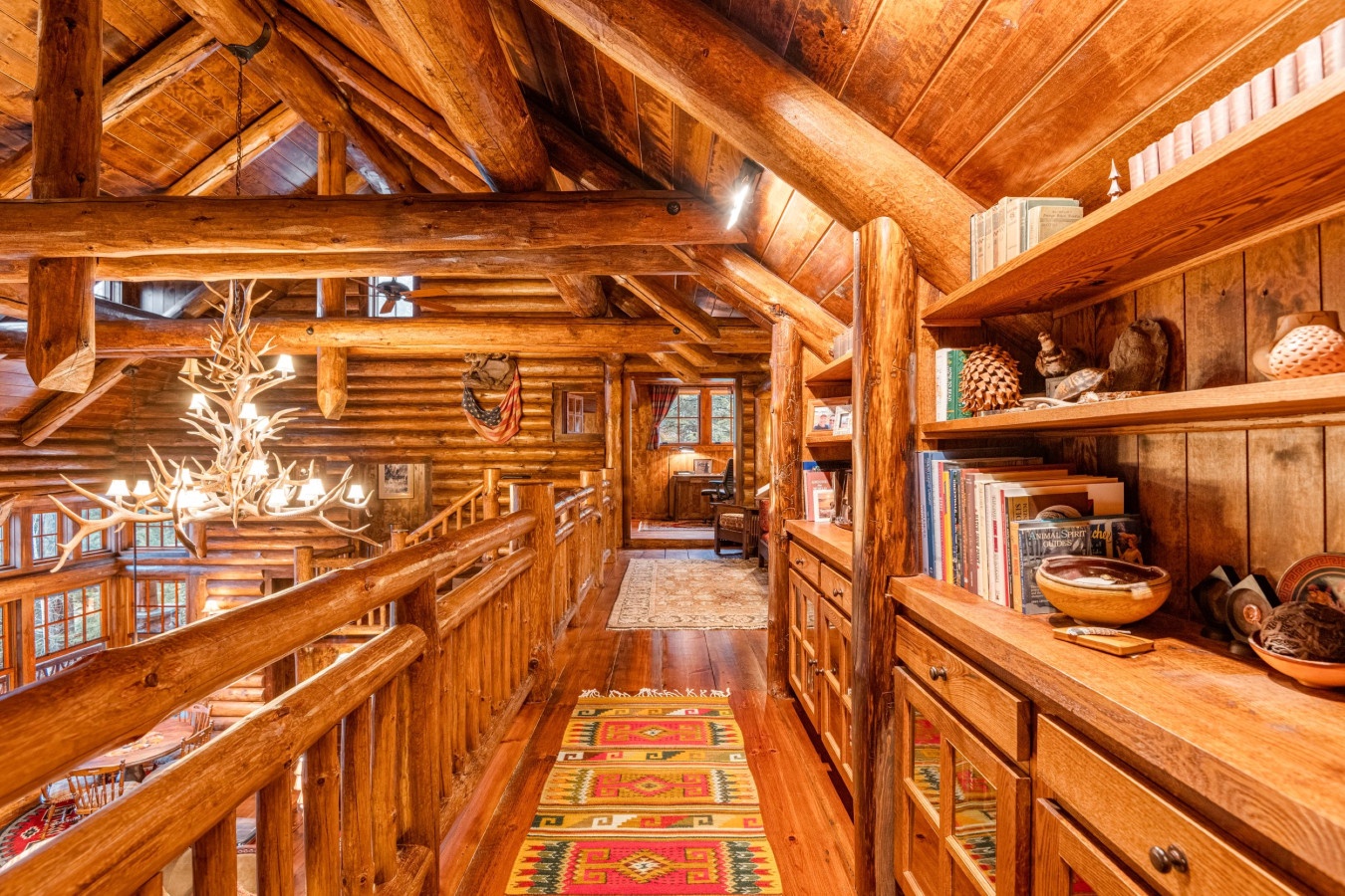 Step into your cozy log cabin loft where rustic timber beams frame shelves of books and treasures, creating the perfect mountain retreat reading nook.