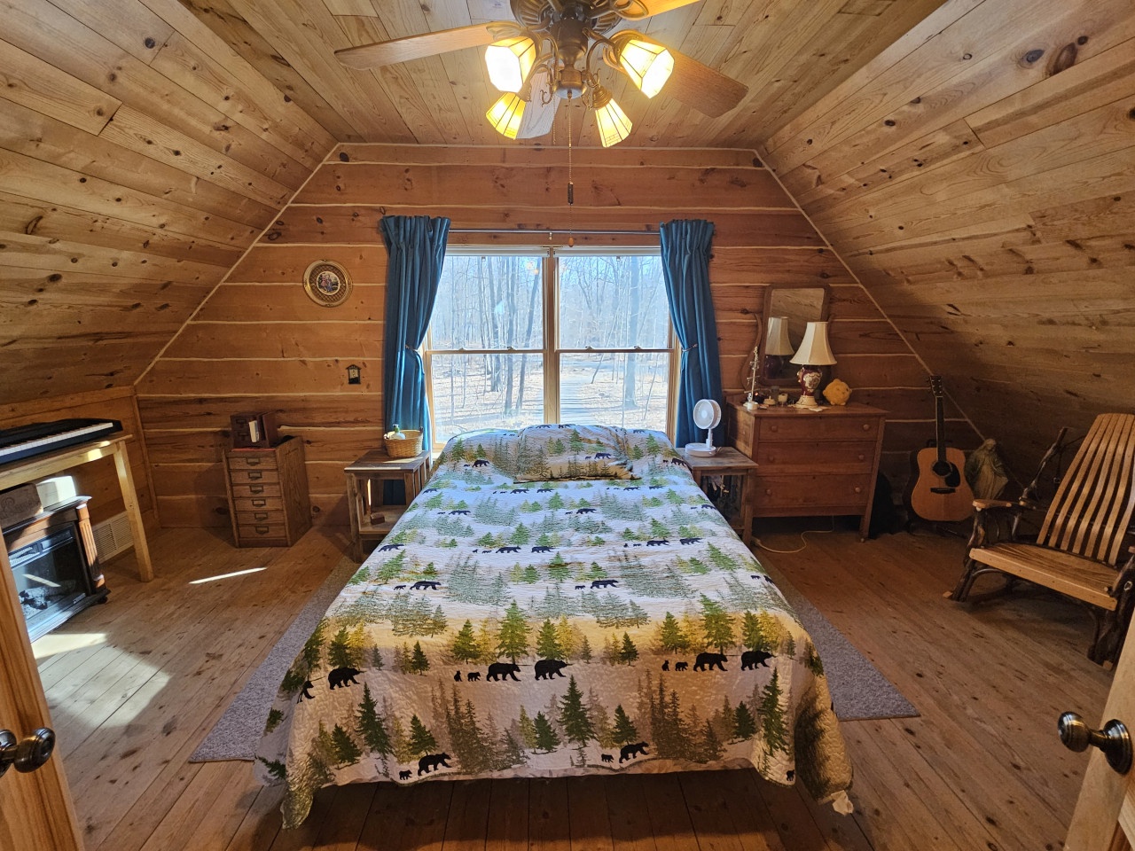 Cozy log cabin bedroom with rustic charm, where warm wood surrounds your peaceful retreat under vaulted ceilings and gentle ceiling fan.