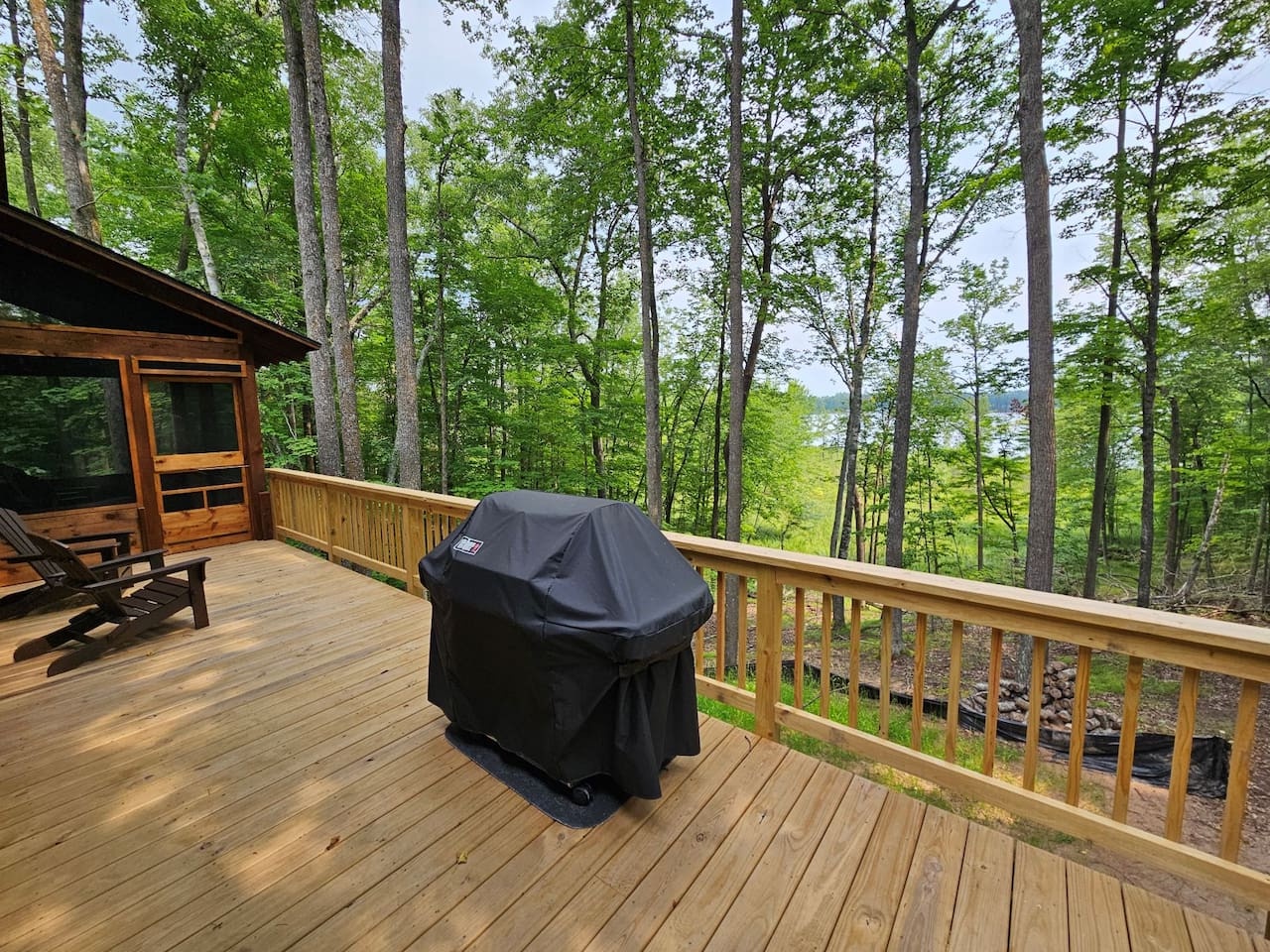 Your private deck overlooks lush forest canopy, complete with a covered grill for woodland barbecues and cozy seating to savor nature's tranquil beauty.