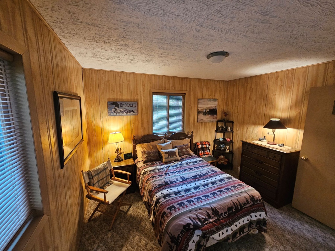 Cozy cabin-style bedroom with warm wood paneling where you'll drift off surrounded by rustic charm and soft lighting.