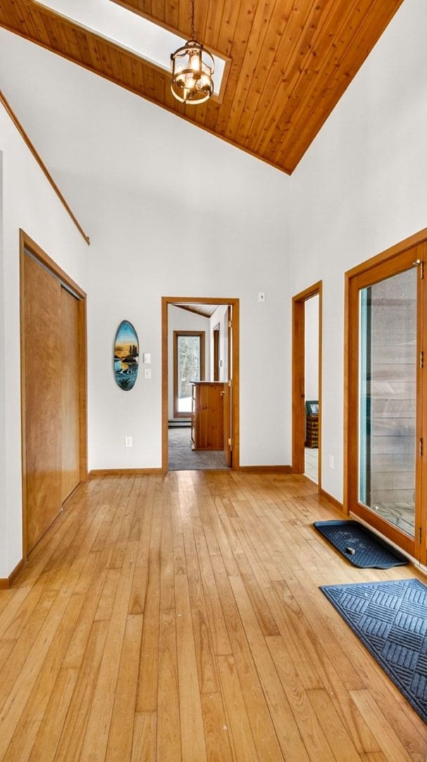 Step into your bright, open entryway where soaring wood ceilings and warm hardwood floors create an instantly welcoming atmosphere.