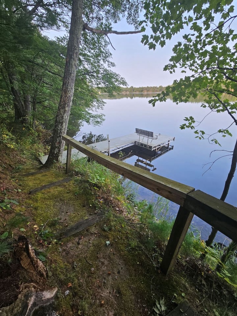 Serene lakefront setting with private dock and wooded trails leading to calm waters perfect for peaceful moments.