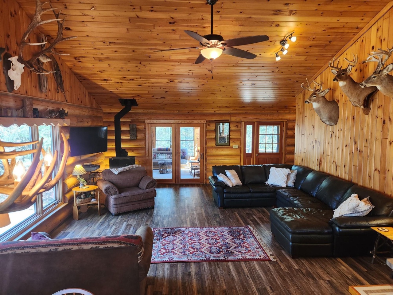 Gather around the cozy sectional sofa in this stunning log cabin living room, where rustic charm meets modern comfort beneath cathedral ceilings.