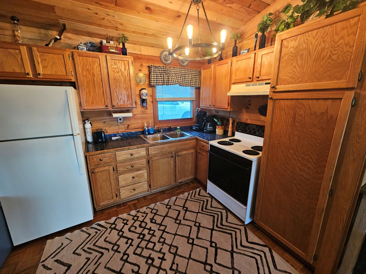 Your fully equipped kitchen features warm wood cabinets, modern appliances, and rustic charm—perfect for preparing cozy meals together.