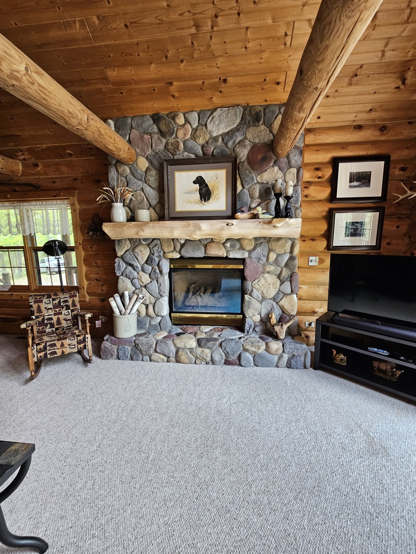 Cozy up by your stone fireplace while watching TV in this rustic log cabin retreat with authentic charm.