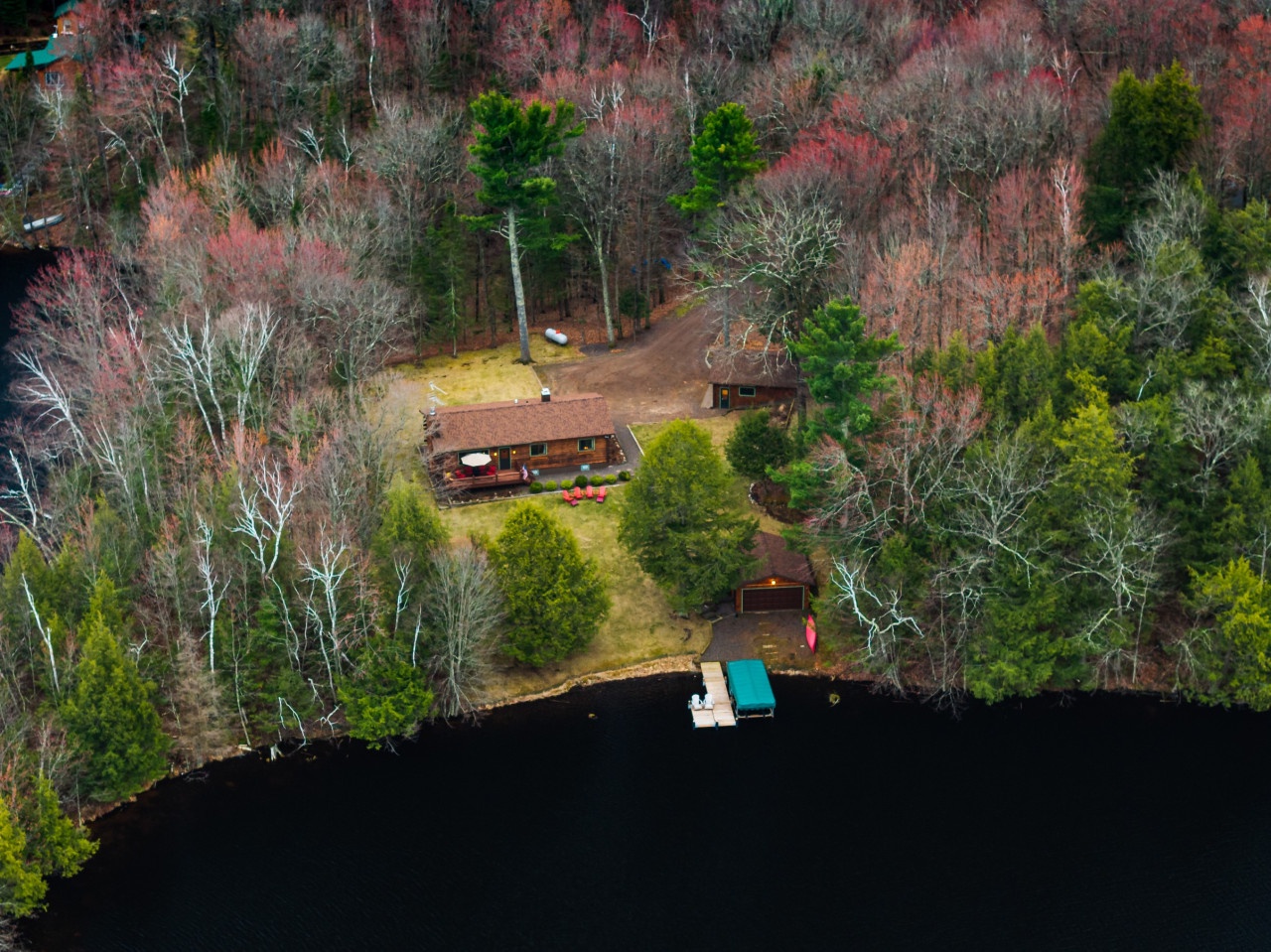 Lakefront property nestled among vibrant autumn foliage with private dock and boat access on pristine waters.