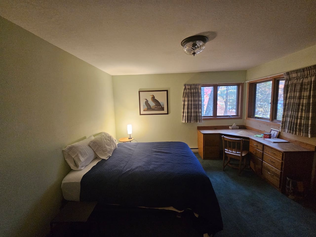 Unwind in your cozy bedroom featuring a comfortable bed, dedicated workspace, and warm lighting for restful nights.