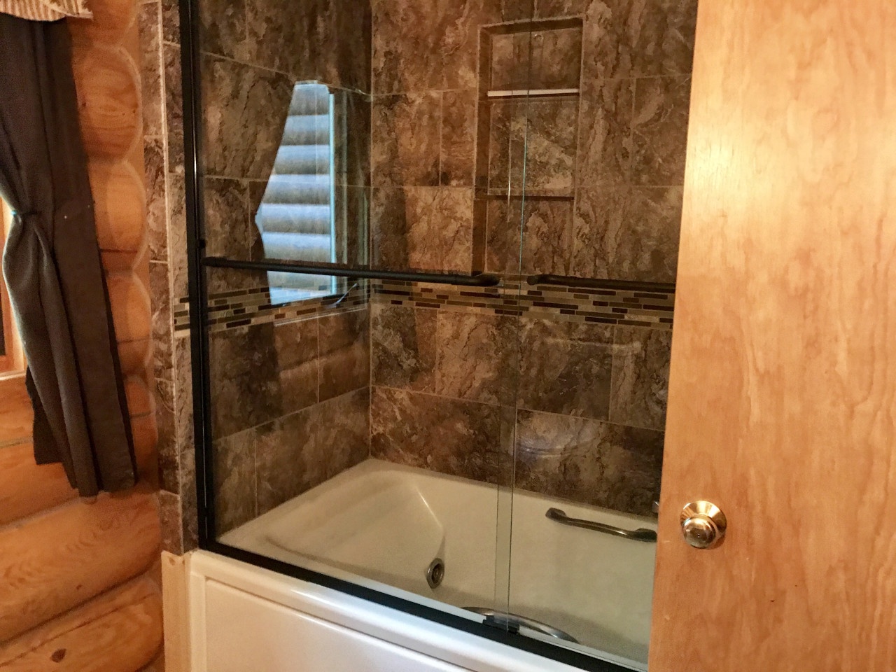 Indulge in luxury with marble-tiled walls, a deep soaking tub, and elegant glass shower doors for your perfect retreat.