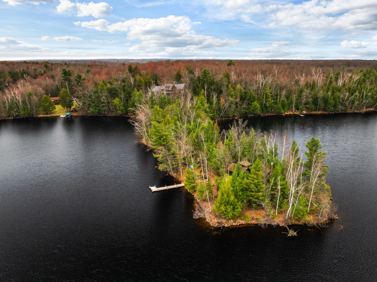 Aerial view of the property's secluded lakefront setting, featuring a private dock and pristine wilderness surroundings.