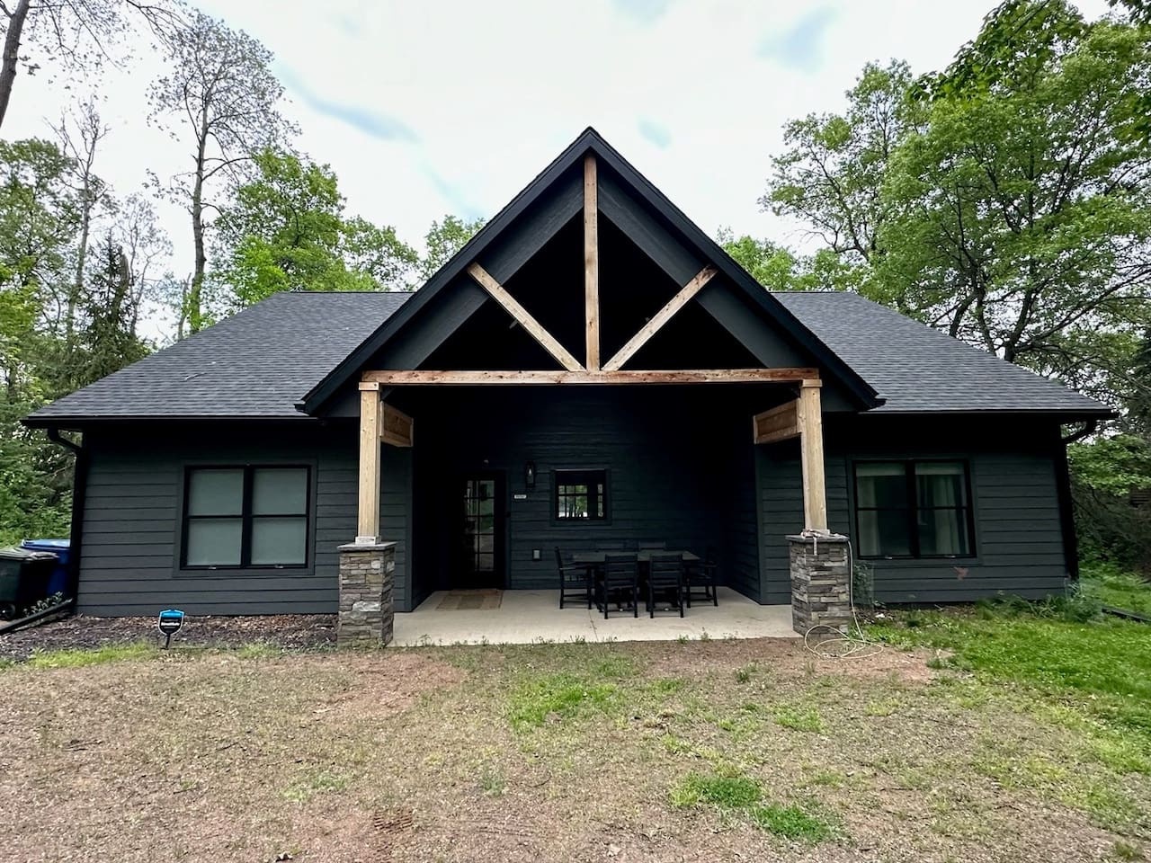 This striking lakehouse features dark exterior siding and rustic timber accents, nestled among towering trees for complete privacy.