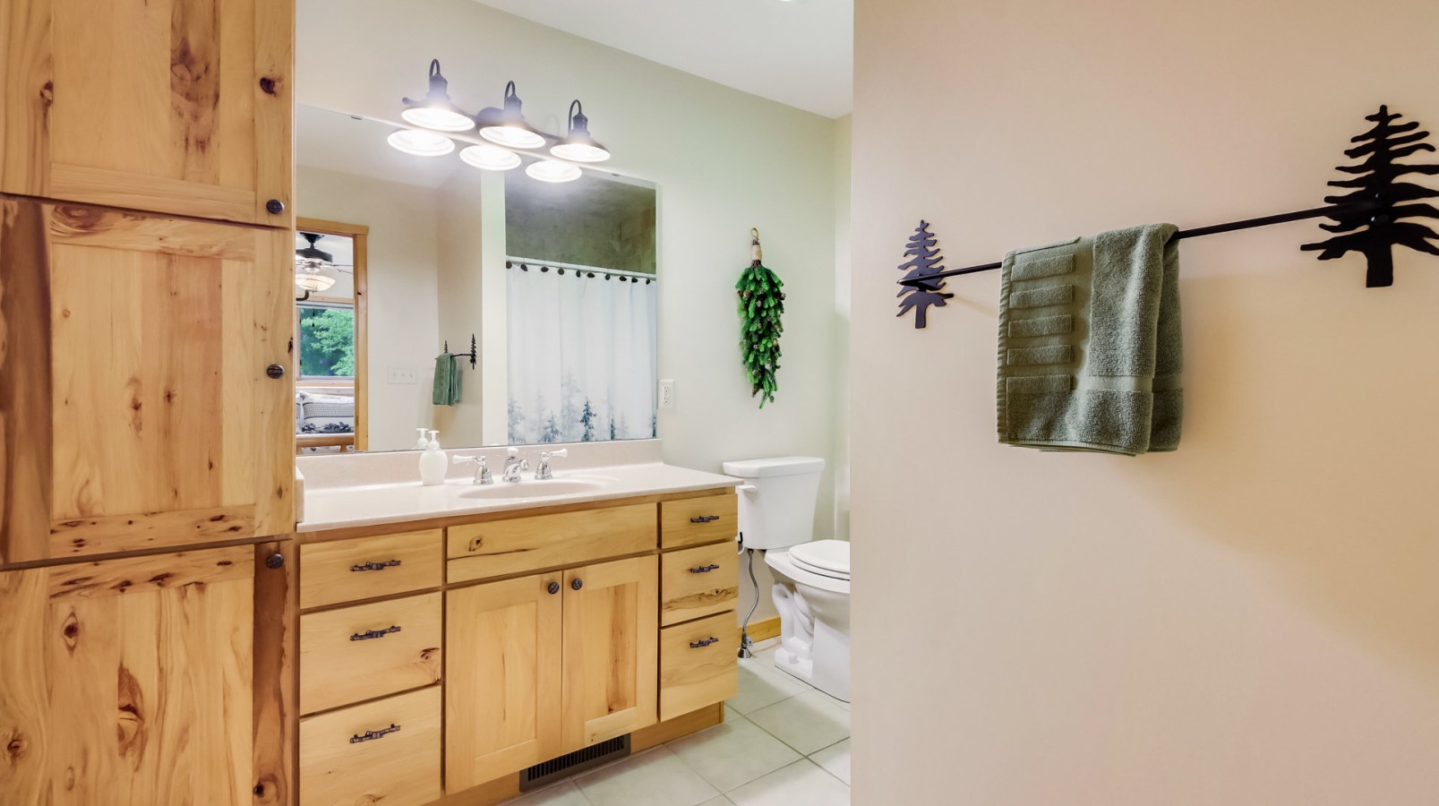 Refresh in your private bathroom with rustic wood vanity, charming forest-themed decor, and modern amenities for a perfect mountain retreat experience.