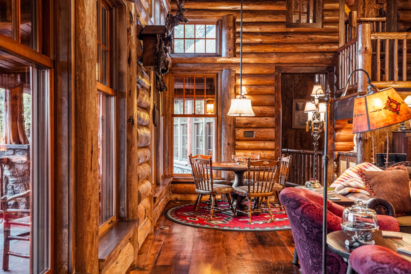 Step into your cozy log cabin retreat where handcrafted wood beams frame intimate dining moments and plush seating invites evening relaxation.