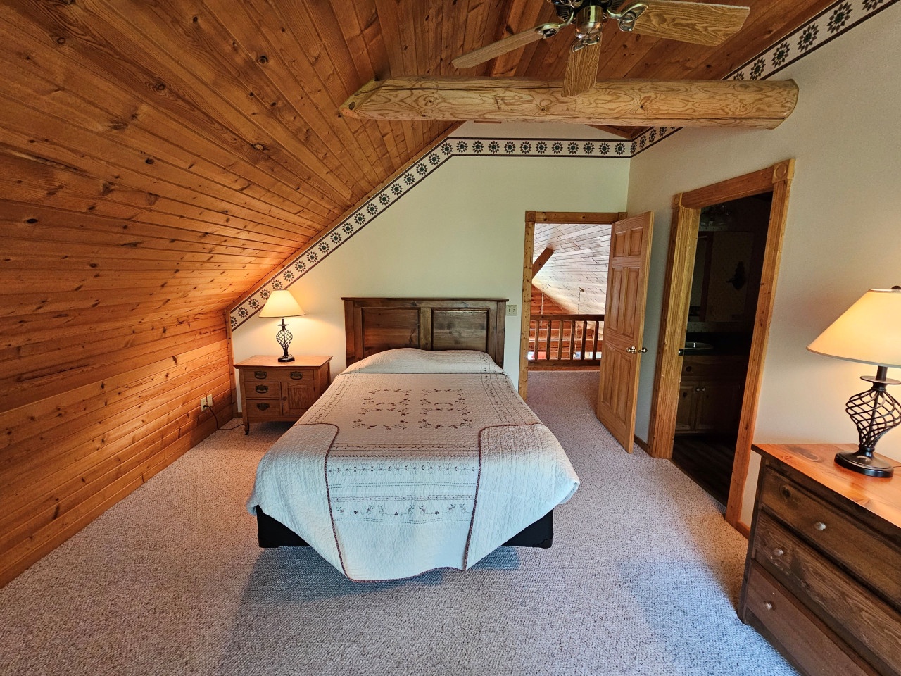 Drift off under exposed wood beams in your cozy attic retreat, where rustic charm meets comfort with a ceiling fan for perfect climate.