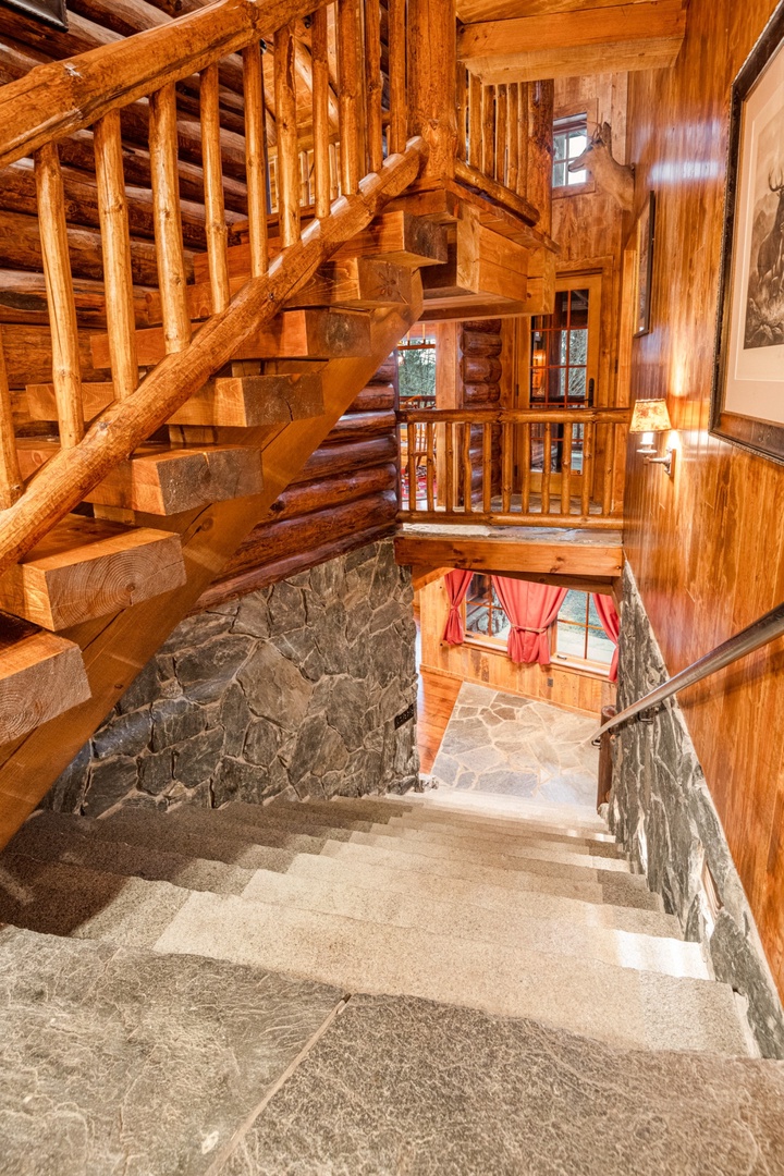 Navigate this handcrafted wooden staircase with rich log beams and stone accents, connecting your mountain retreat's levels with rustic elegance.