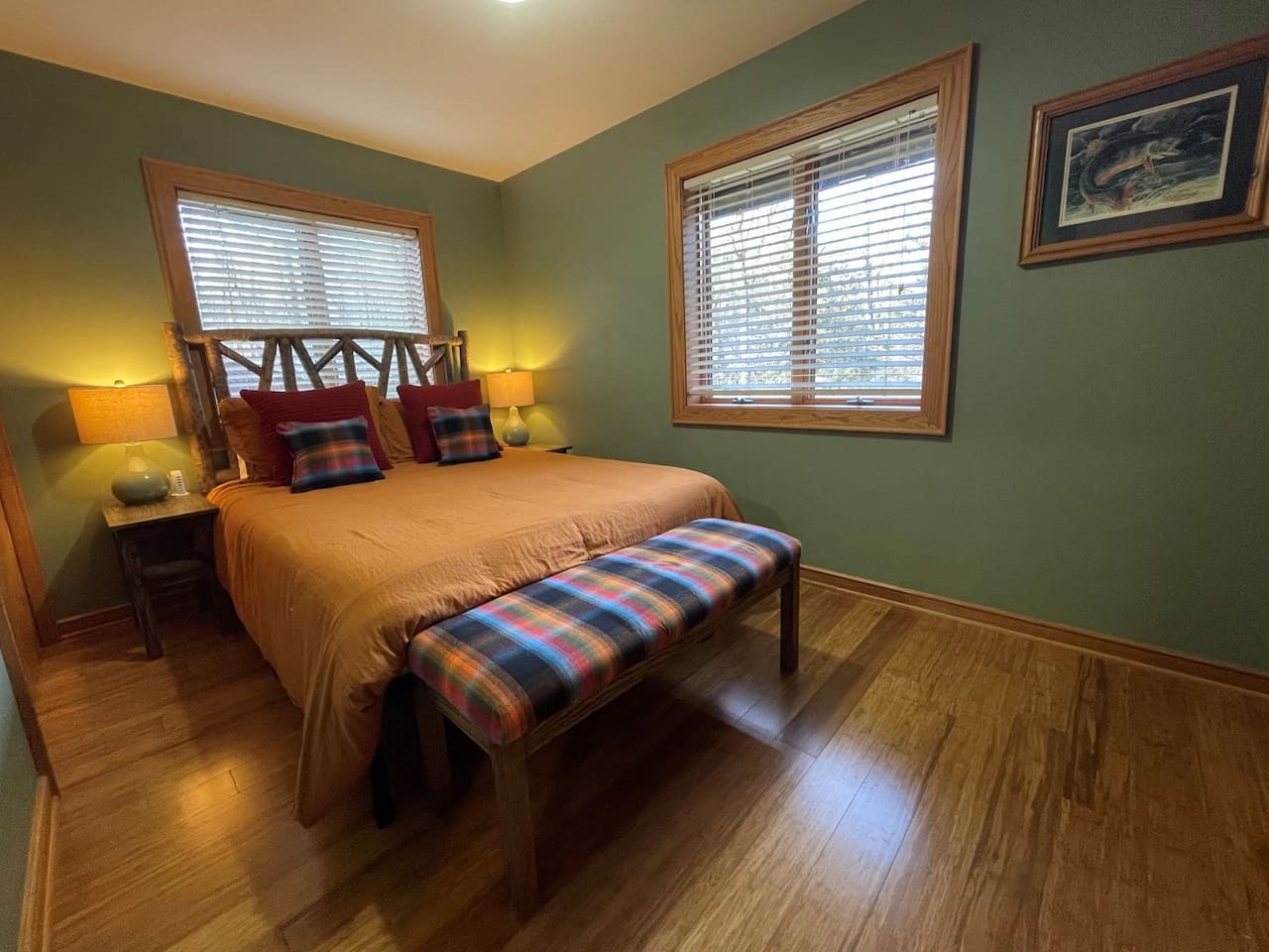 Sink into your cozy rustic bedroom with warm cabin charm, complete with plaid accents and peaceful forest views.