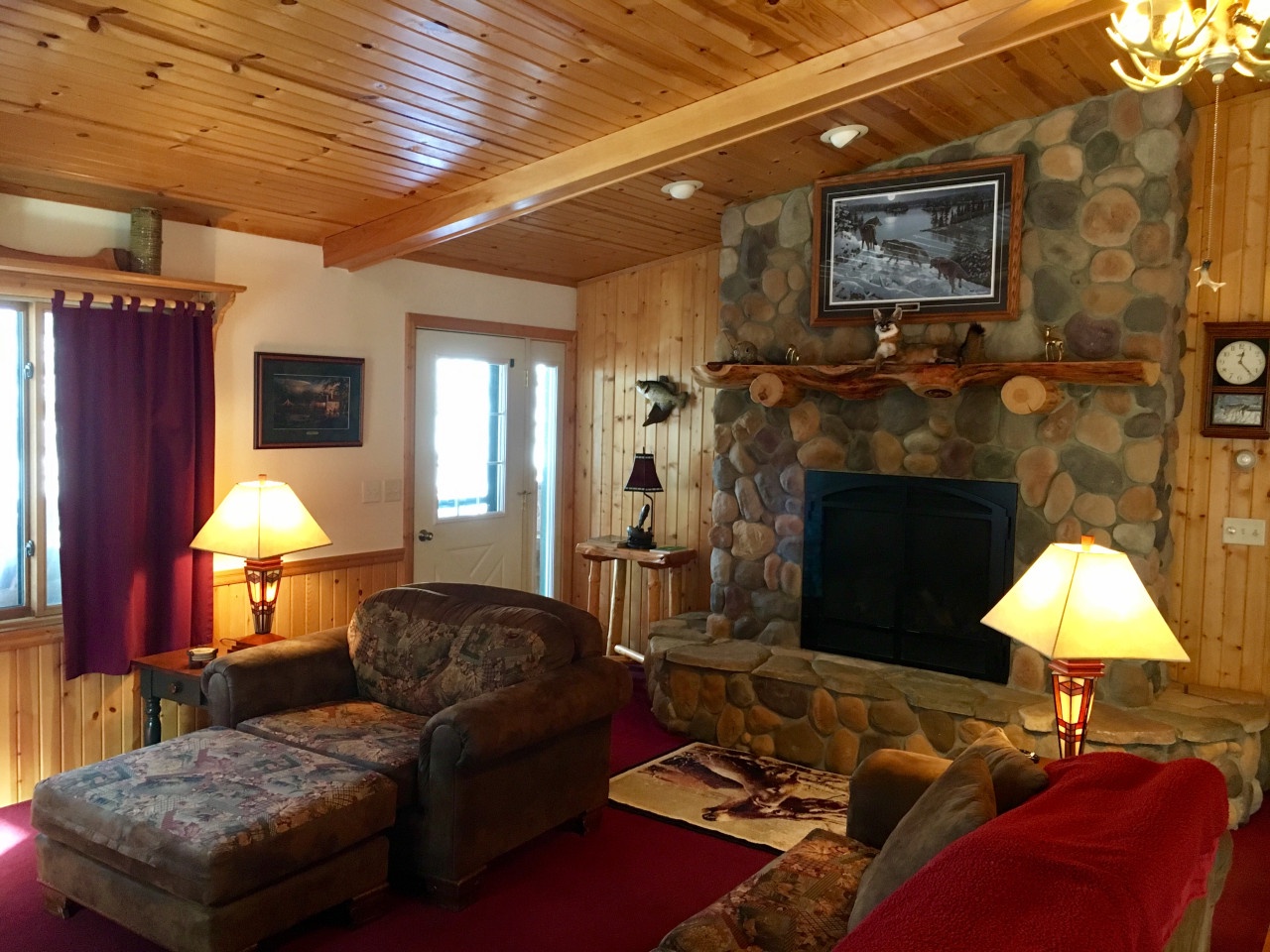 Curl up by your stone fireplace in this cozy cabin living room with rustic wood beams and warm lamp light.