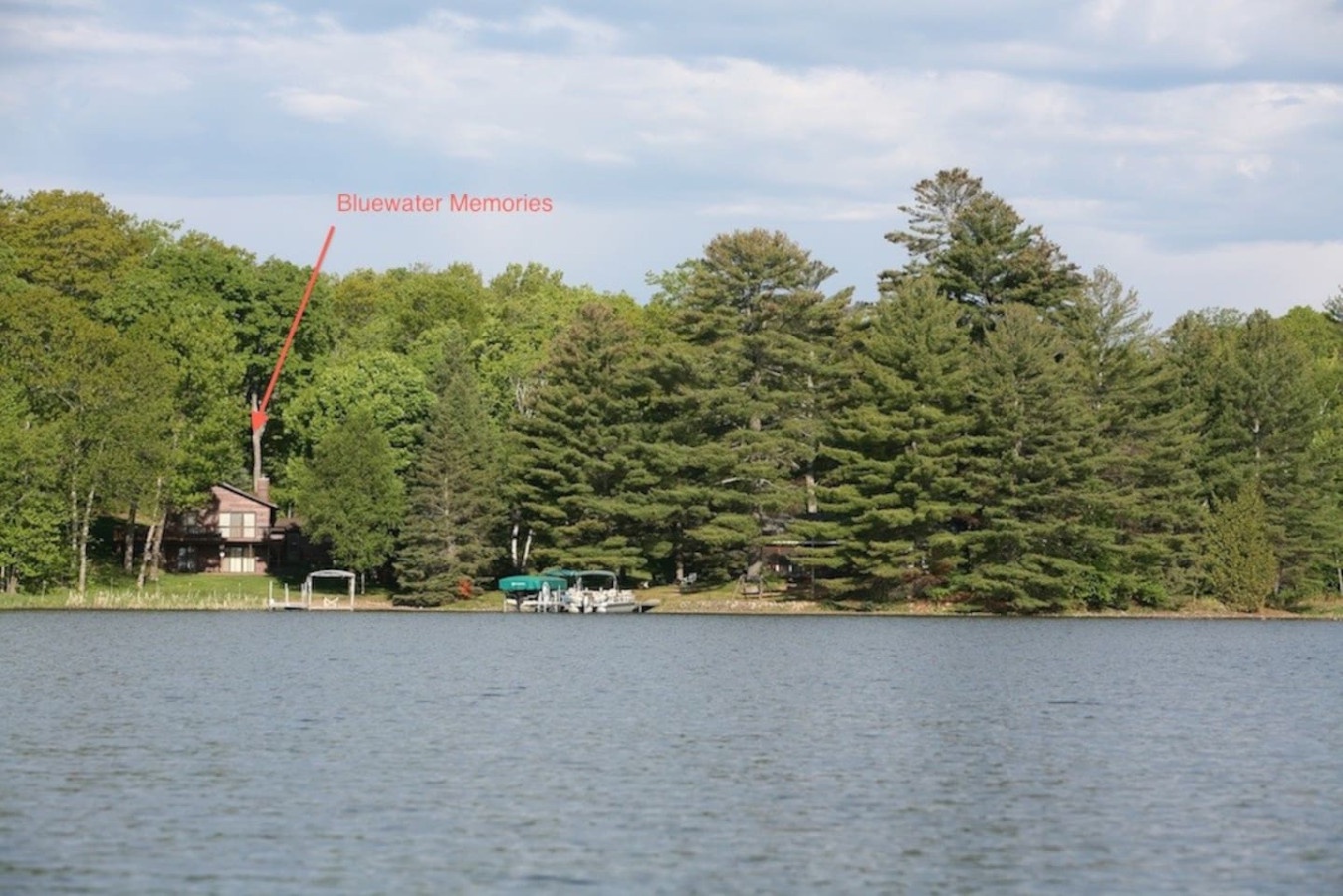 Peaceful lakefront setting with pristine waters surrounded by lush forest and waterfront properties.