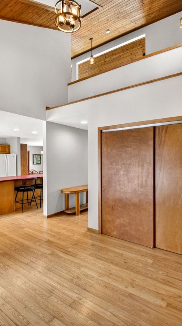 Step into your spacious open-concept living area where warm wood beams frame soaring ceilings and natural light dances across gleaming hardwood floors.