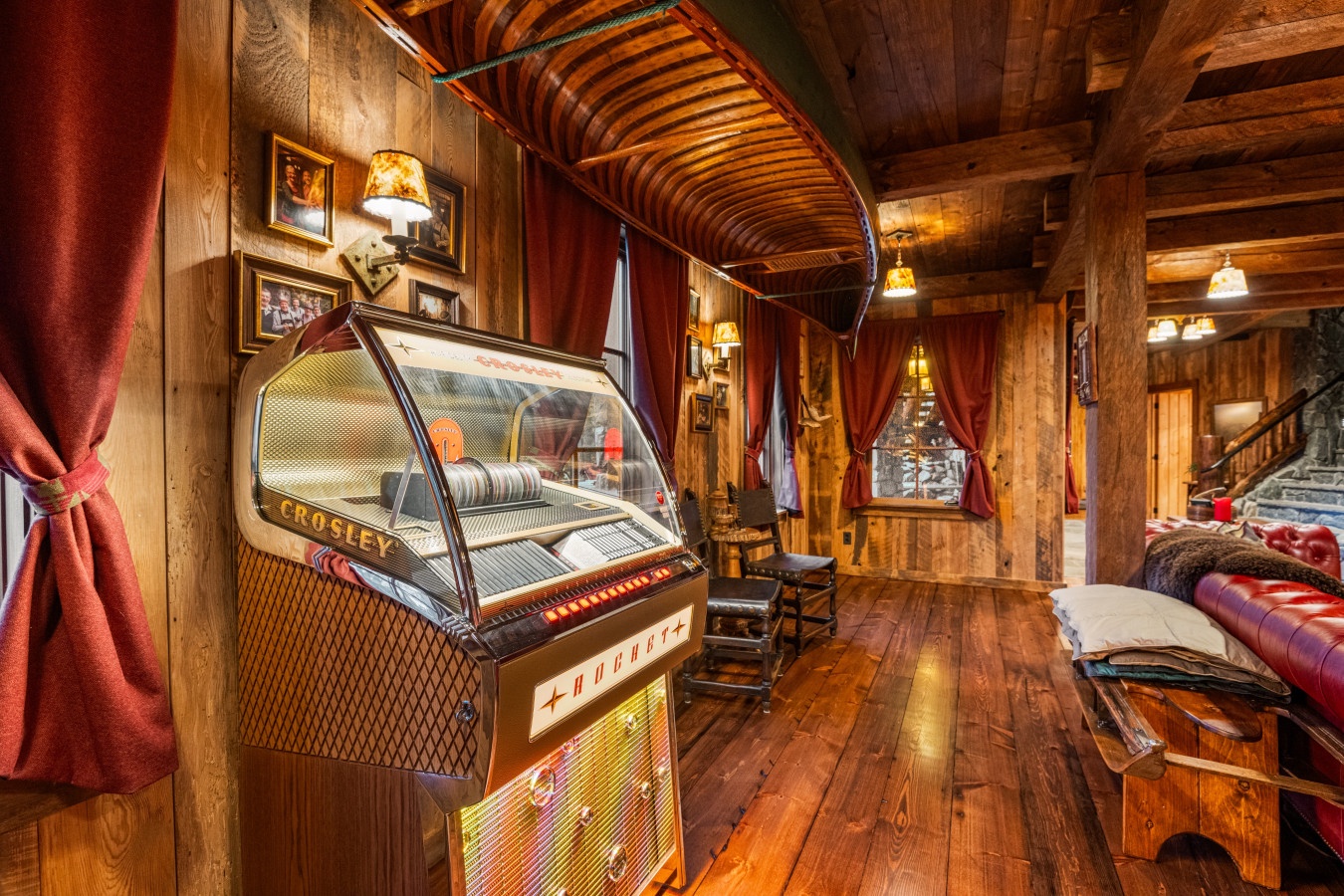 Step into your rustic entertainment room featuring a vintage jukebox, exposed wooden beams, and cozy seating perfect for memorable evenings.