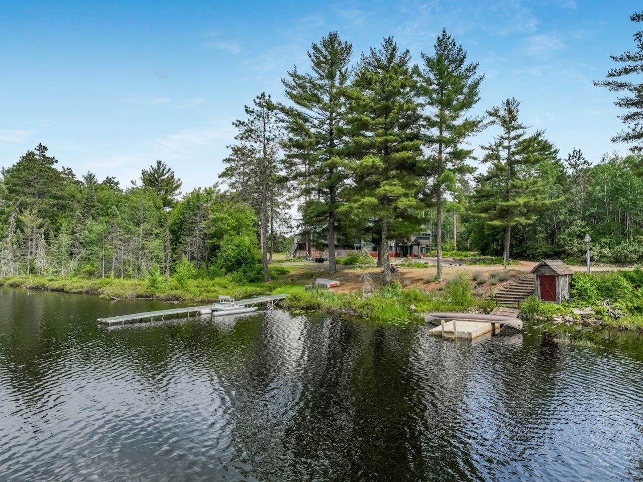Lakefront property featuring private dock and swimming platform surrounded by towering pines and pristine wilderness.
