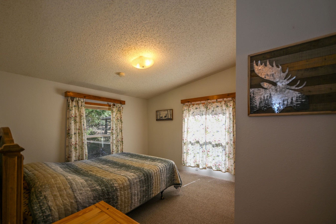 Drift off to sleep beneath the watchful gaze of majestic moose artwork in your cozy retreat with rustic charm.