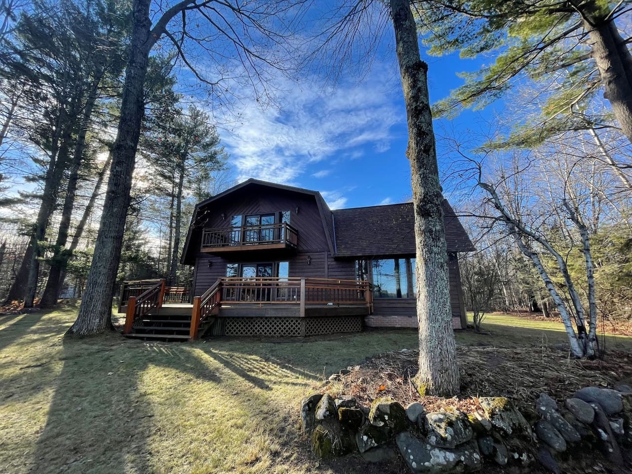 Charming lakeside cabin nestled among towering pines, featuring rustic wood siding and expansive decks for peaceful forest moments.