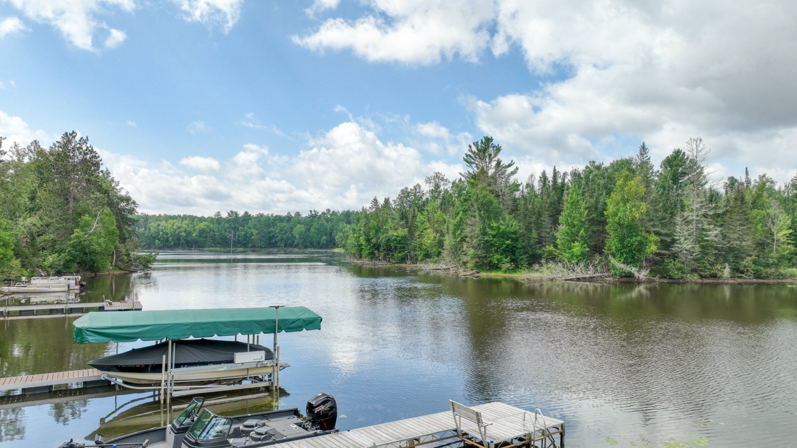 Peaceful lake setting with private dock and boats, surrounded by lush forest—perfect for tranquil waterfront getaways.