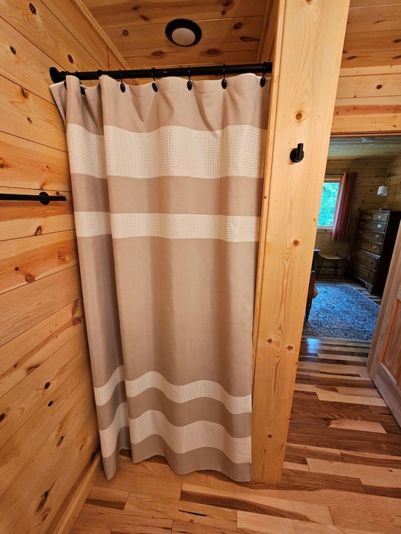 Enjoy your private shower in this cozy cabin bathroom, surrounded by warm natural wood that creates the perfect rustic retreat atmosphere.