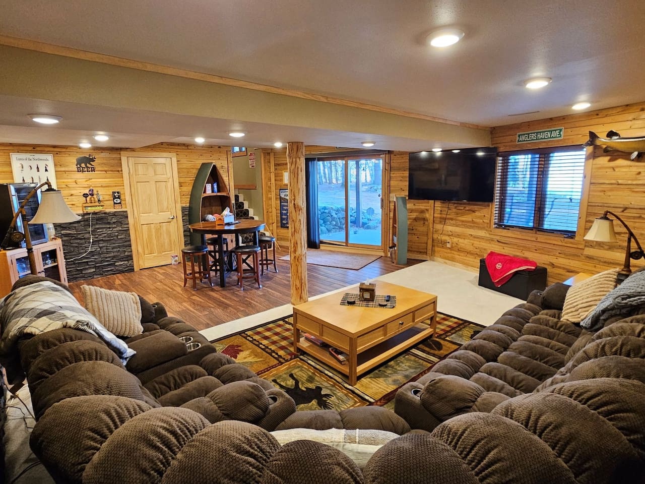 Sink into plush recliners in your rustic retreat's spacious great room, where warm wood walls and mountain views create perfect comfort.