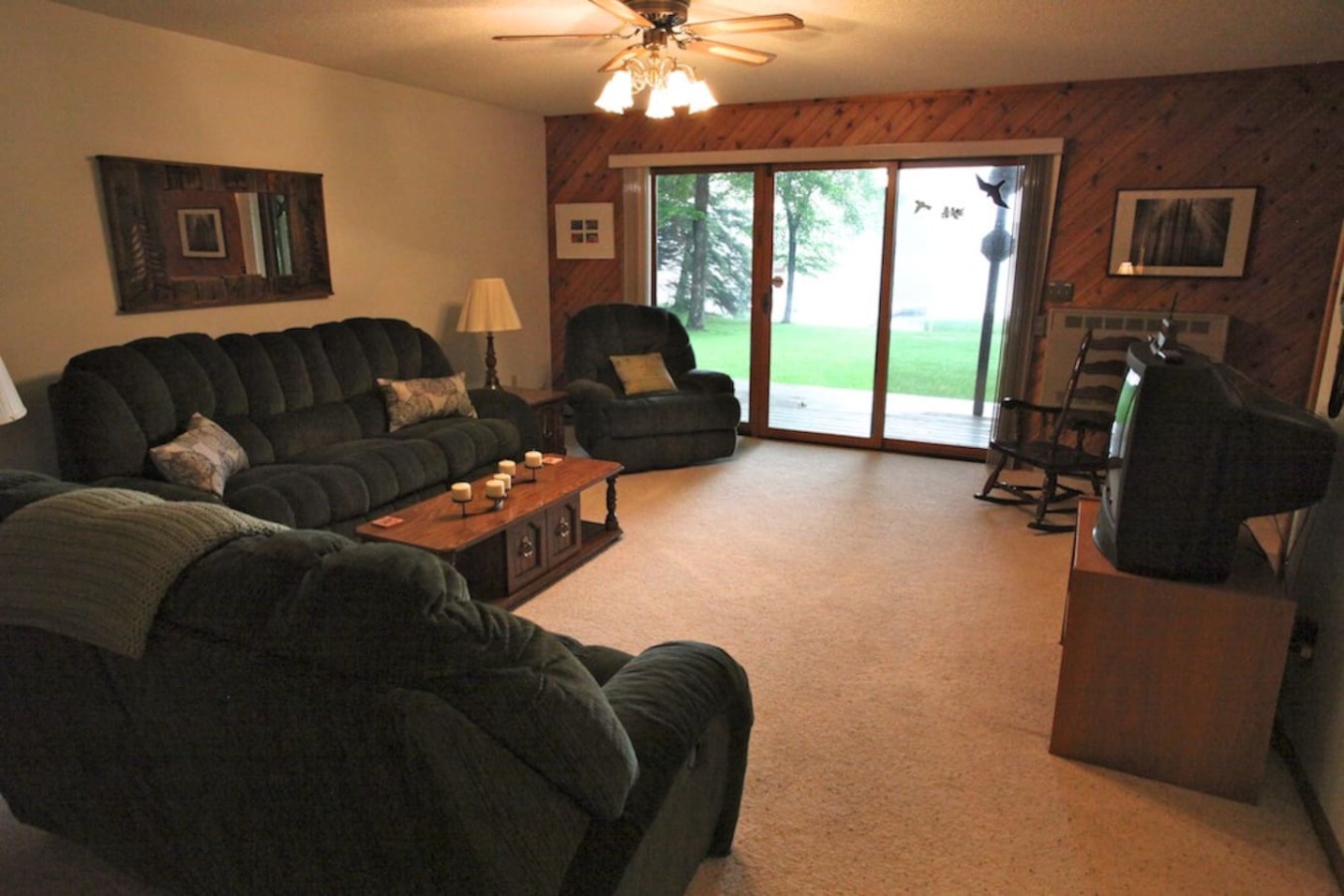 Unwind in your spacious living room with plush seating, ceiling fan, and sliding doors opening to a peaceful yard view.