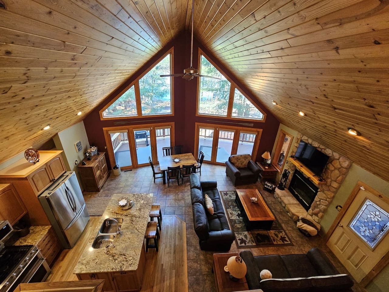 Your cozy mountain retreat features soaring wood-beam ceilings, a stone fireplace, and panoramic windows overlooking winter wonderland views.