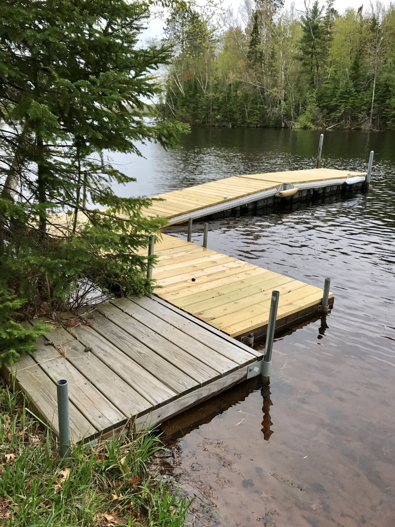 A private dock extends into calm lake waters, surrounded by lush forest—your perfect launch point for peaceful mornings and evening reflections.