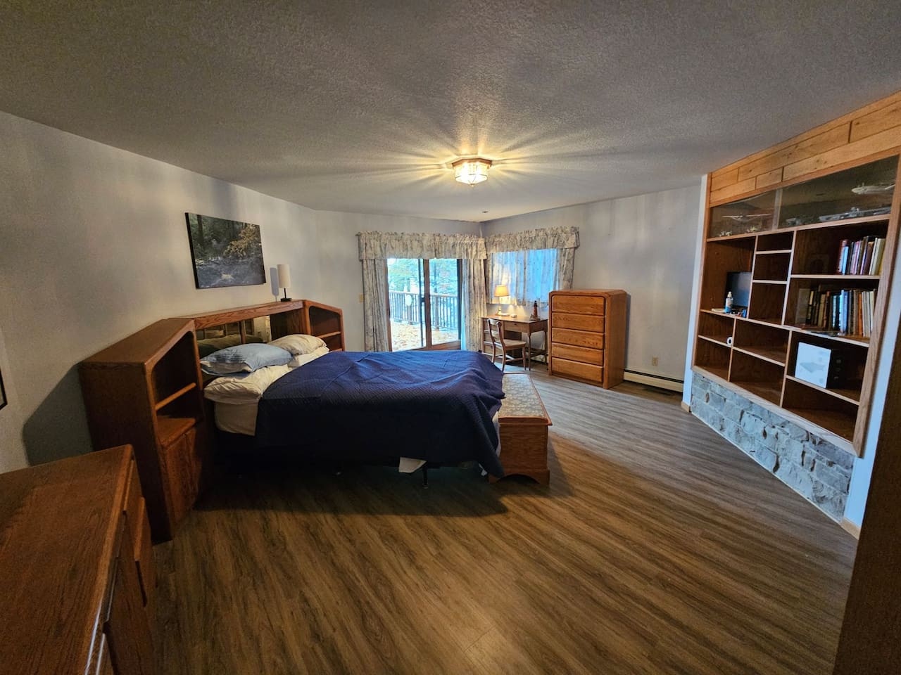 Unwind in your spacious bedroom with handcrafted wooden furniture, built-in library shelves, and peaceful balcony access for morning coffee or evening relaxation.