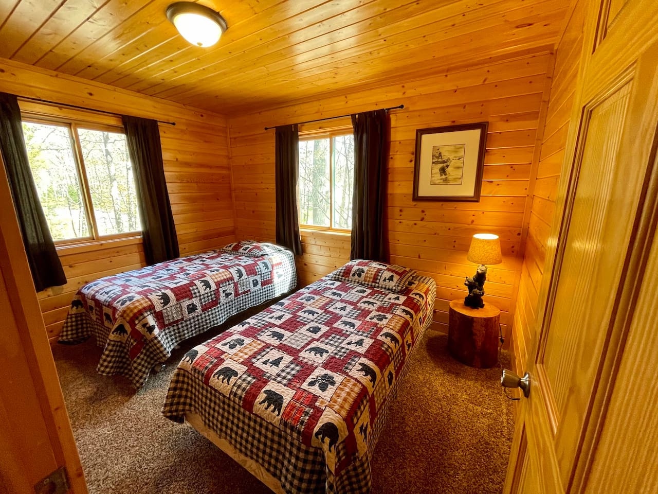 Rest easy in your cozy twin bedroom with charming cabin quilts and warm wood surroundings that create the perfect mountain retreat atmosphere.