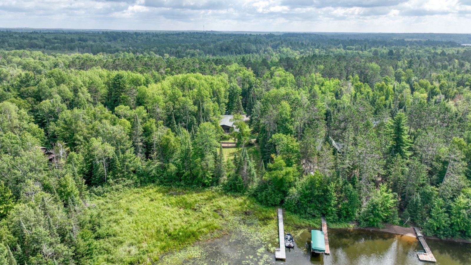 Aerial view of a secluded lakefront property surrounded by pristine wilderness and dense forest canopy.