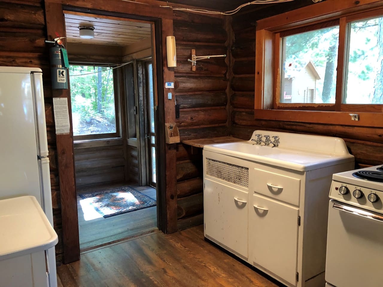 Step into your cozy log cabin kitchen where rustic charm meets modern convenience, surrounded by warm wood walls and forest views.