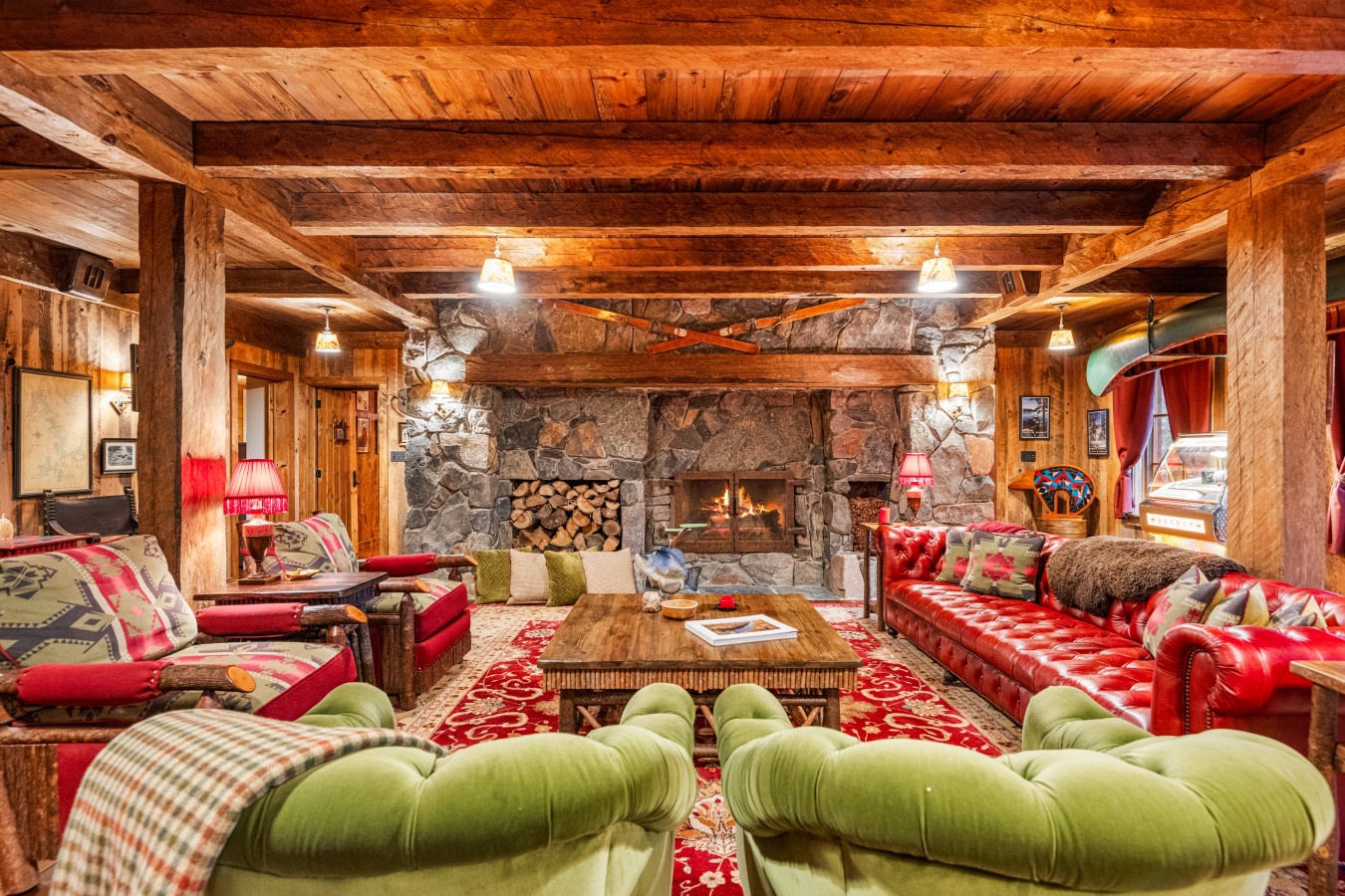 Cozy up in this stunning alpine living room with crackling stone fireplace, rich leather seating, and rustic wood beams overhead.