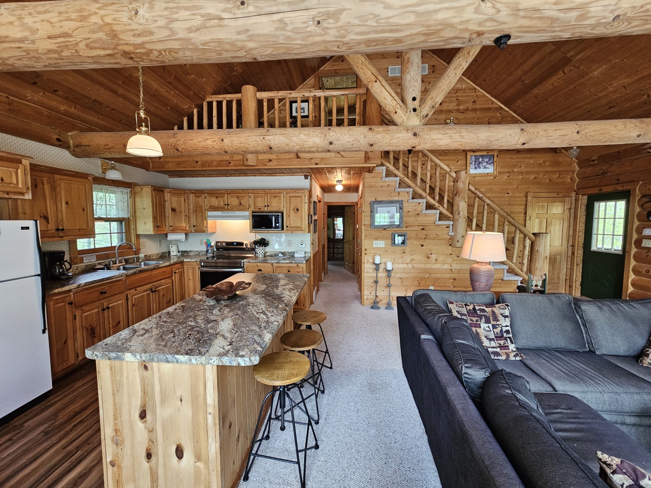 Your rustic retreat awaits with exposed timber beams, granite island seating, and cozy living space perfect for mountain getaway memories.