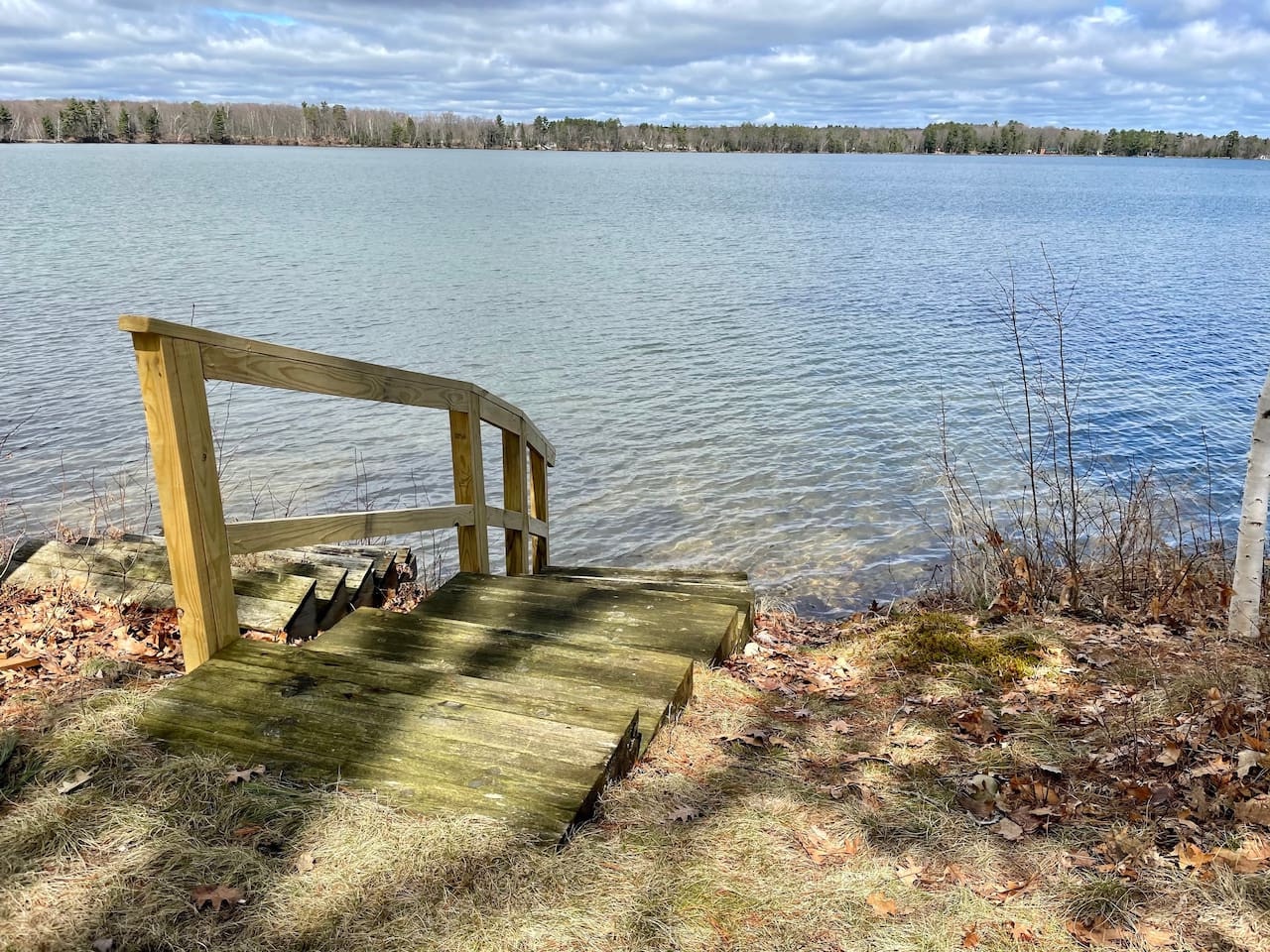 Peaceful lake setting with private dock platform surrounded by natural forest landscape and open water views.