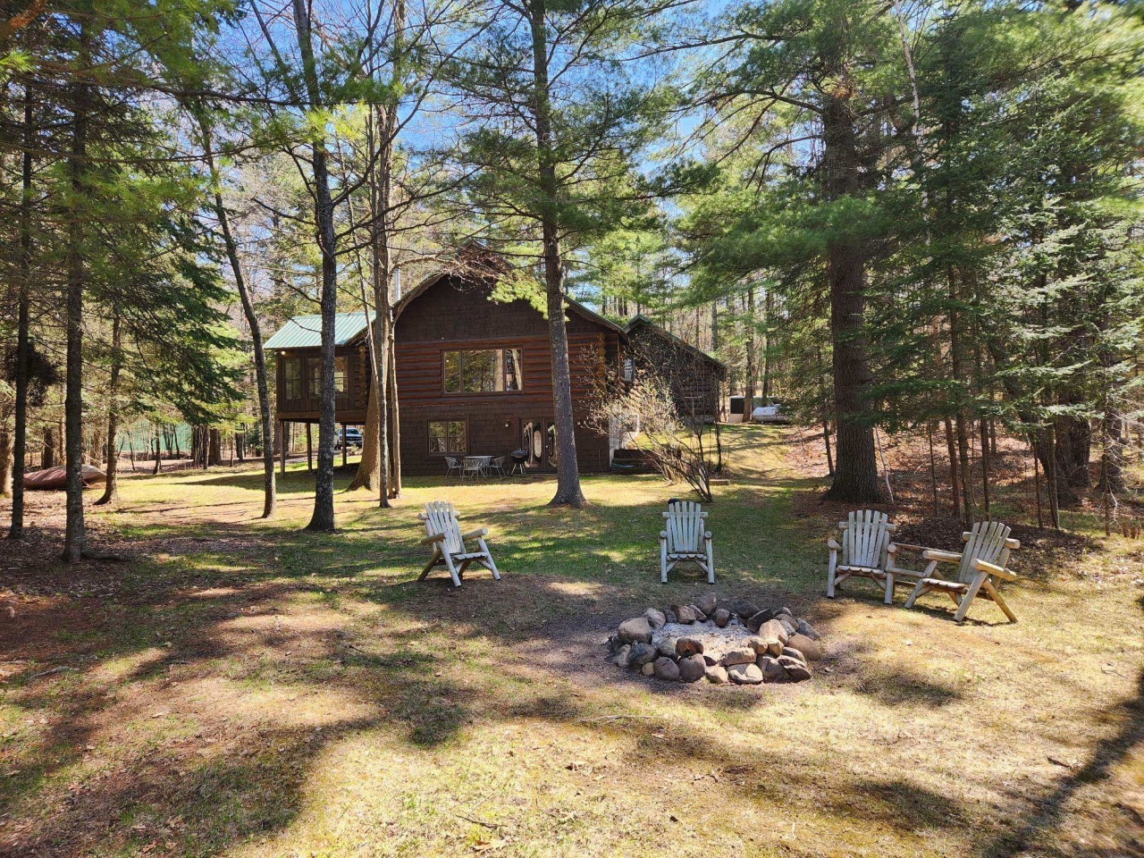 Rustic cabin retreat nestled in towering pines with outdoor fire pit and Adirondack chairs for memorable evenings under the stars.