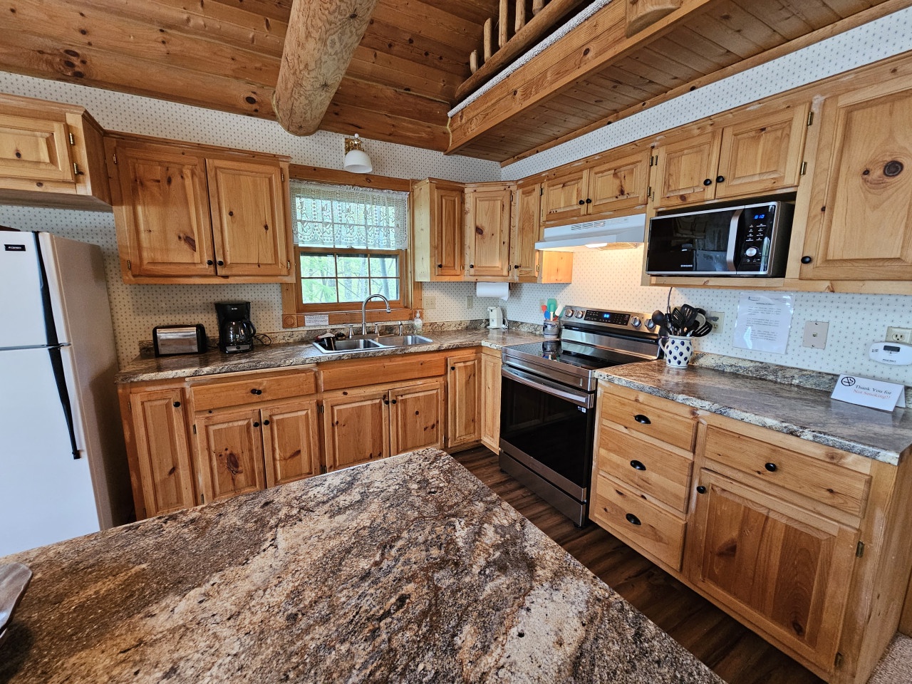 Step into your rustic kitchen with knotty pine cabinets, granite countertops, and exposed wood beams creating the perfect mountain retreat atmosphere.
