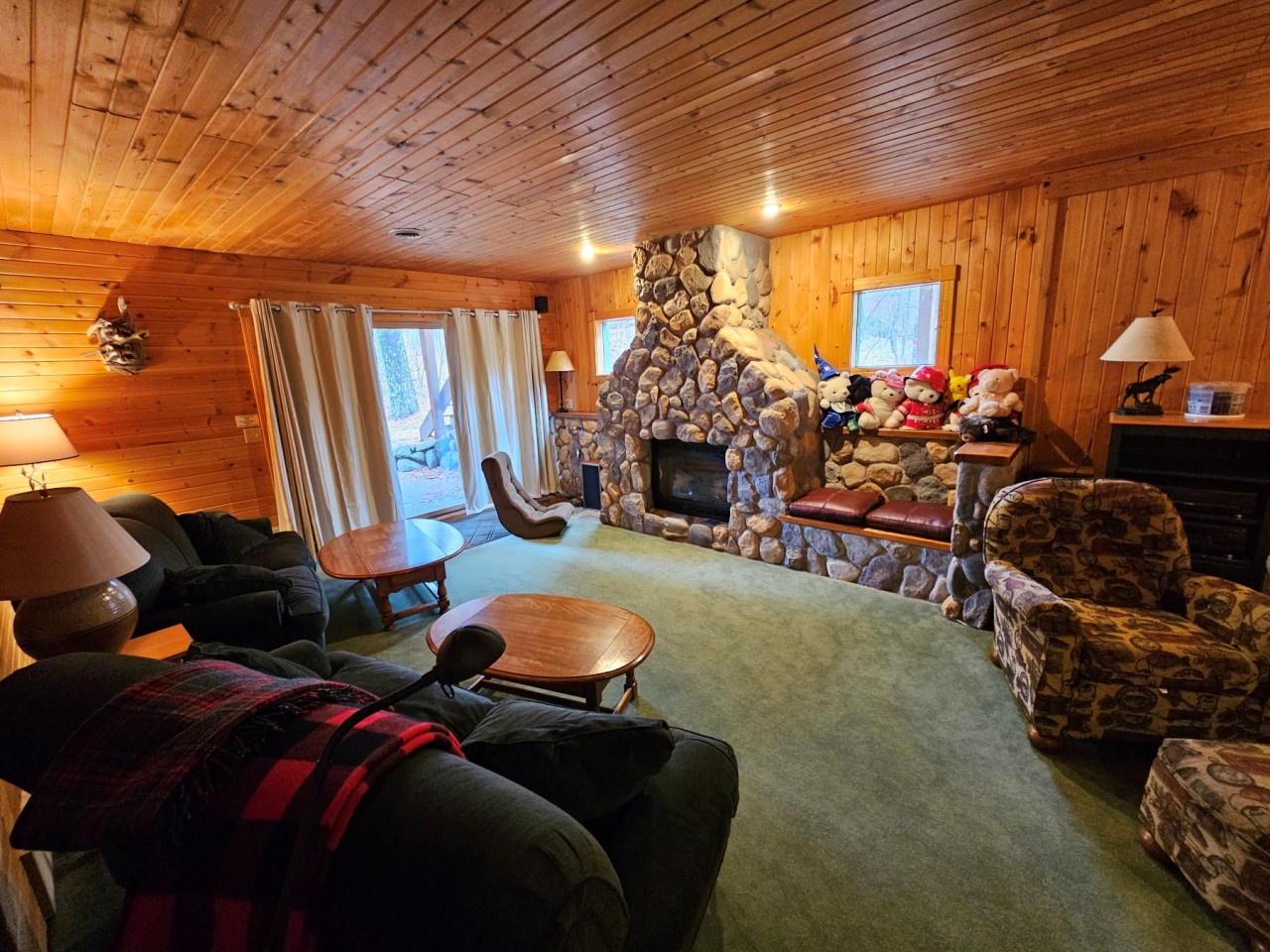 Cozy up in your rustic living room with a magnificent stone fireplace, warm wood walls, and soft seating perfect for mountain evenings.