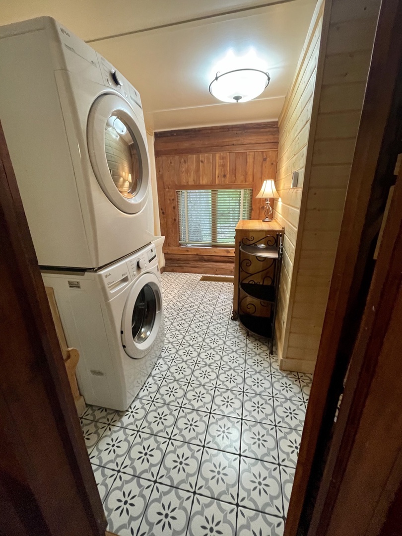 Your dedicated laundry room features stacked washer and dryer units, charming patterned tiles, and rustic wood paneling for convenient home-away-from-home care.